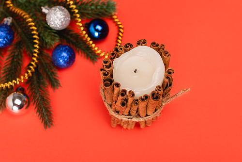 top view of decorated Christmas tree and candle on red background