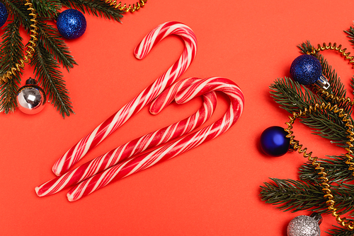 top view of decorated Christmas tree and candy canes on red background