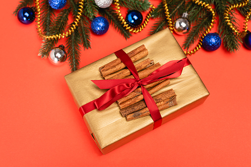 top view of decorated Christmas tree, gift with cinnamon on red background