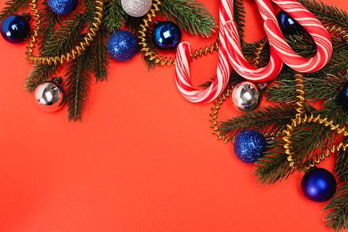 top view of decorated Christmas tree and candy canes on red background