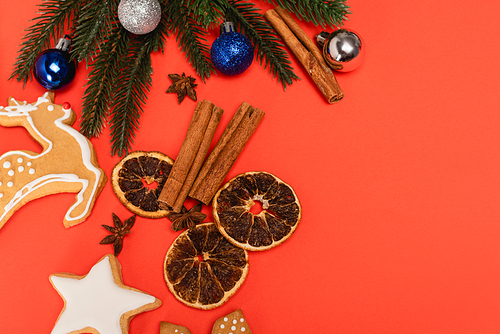 top view of Christmas tree, spices and gingerbread cookies on red background