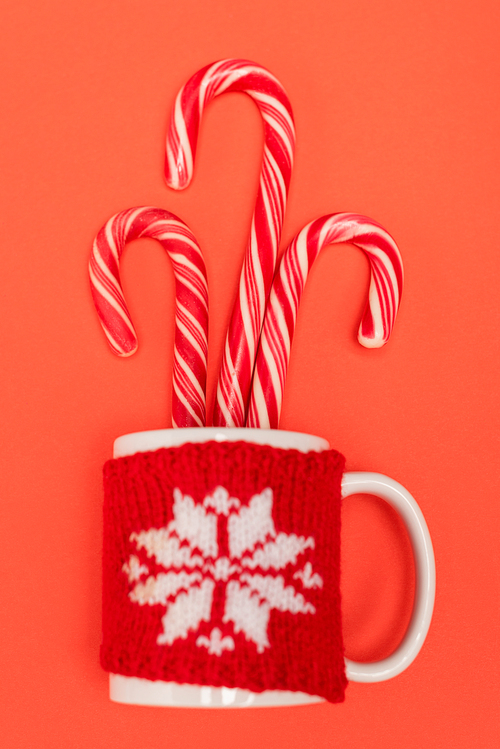 top view of candy canes in mug on red background