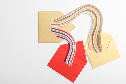 top view of yellow and red envelopes with multicolored rainbow on grey background