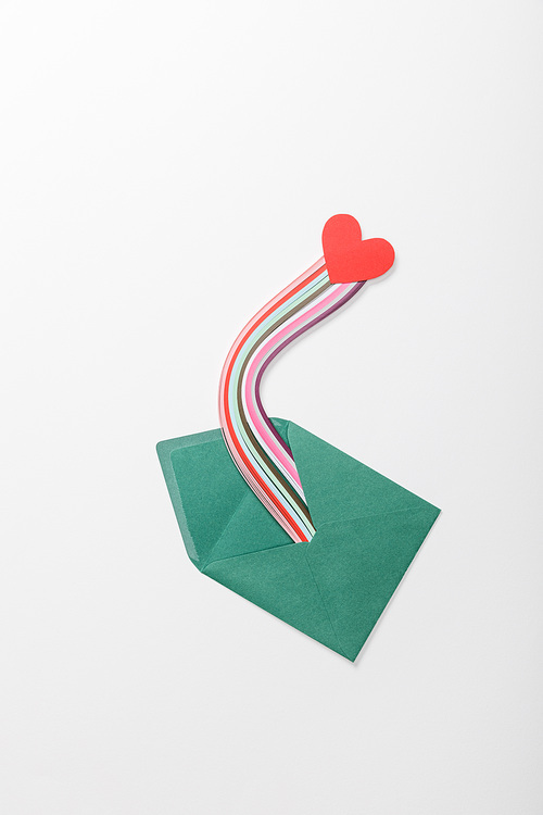top view of green envelope with multicolored rainbow and heart sign on grey background