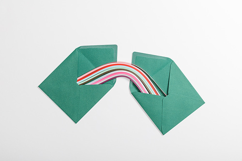 top view of green envelopes with multicolored rainbow on grey background