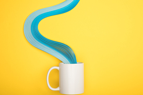 top view of white cup and blue curved lines on yellow background