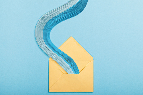 top view of blue curved abstract paper lines and yellow envelope on blue background