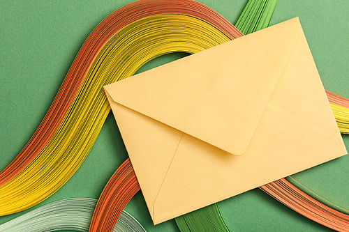 top view of multicolored abstract lines on green background with yellow envelope