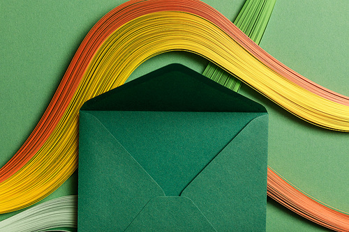 top view of multicolored abstract lines on green background with green opened envelope