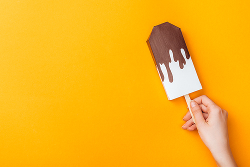cropped view of young woman holding paper ice cream isolated on orange with copy space