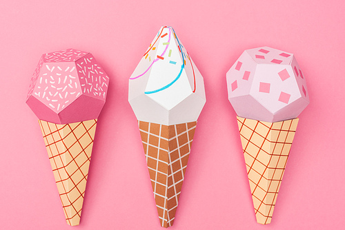 top view of handmade colorful origami ice cream cones isolated on pink