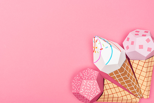 top view of handmade colorful origami ice cream cones isolated on pink with copy space