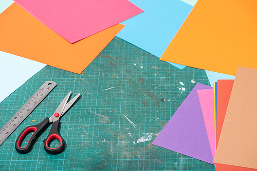 colorful cardboard with scissors and ruler on messy surface