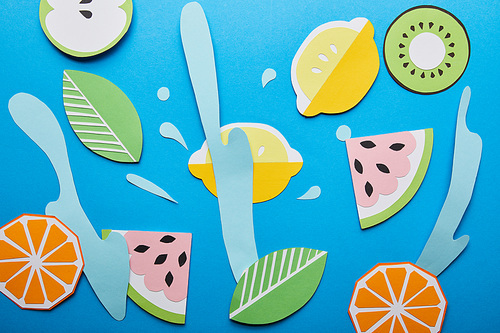 top view of paper cut water splashes with fruits on blue background