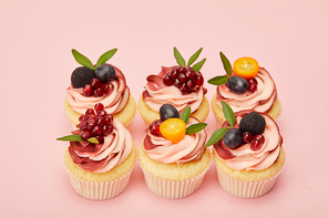 sweet cupcakes with fruits and berries on pink surface
