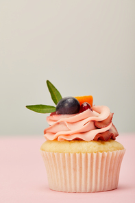 tasty cupcake with cream and fruits on pink surface isolated on grey