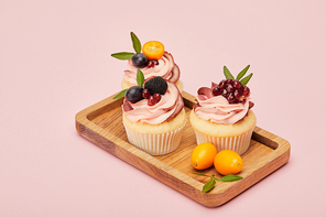 sweet cupcakes with berries and fruits isolated on pink