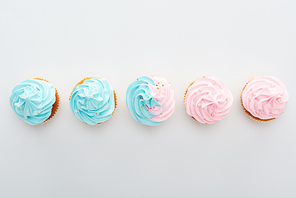 top view of tasty colorful cupcakes with sprinkles in row Isolated On White