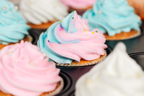 close up of delicious blue and pink cupcakes decorated with sprinkles in cupcake tray