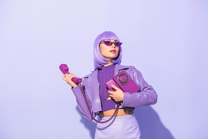 young woman dressed in doll style with retro telephone on violet colorful background