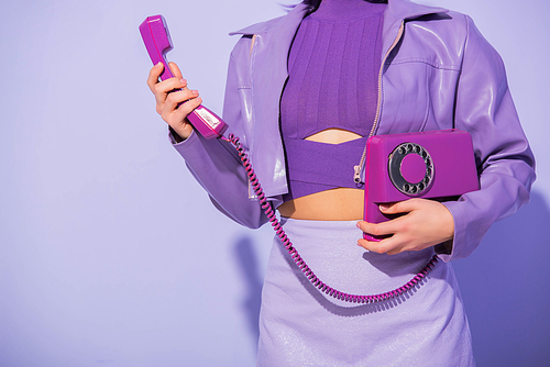 cropped view of young woman dressed in doll style with retro telephone on violet colorful background