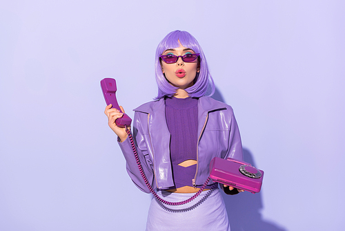 surprised young woman dressed in doll style with retro telephone on violet colorful background