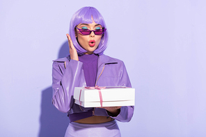 shocked young woman dressed in doll style with cupcake box on violet colorful background