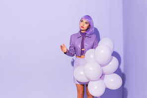 young woman dressed in doll style with balloons on violet colorful background