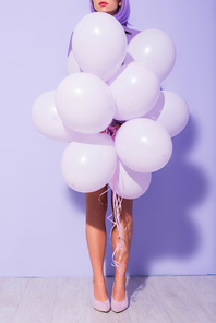 cropped view of young woman dressed in doll style with balloons on violet colorful background