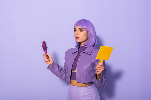 young woman dressed in doll style with hair brush and mirror on violet colorful background