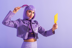 young woman dressed in doll style with hair brush and mirror on violet colorful background