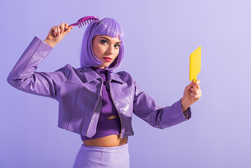 young woman dressed in doll style with hair brush and mirror on violet colorful background