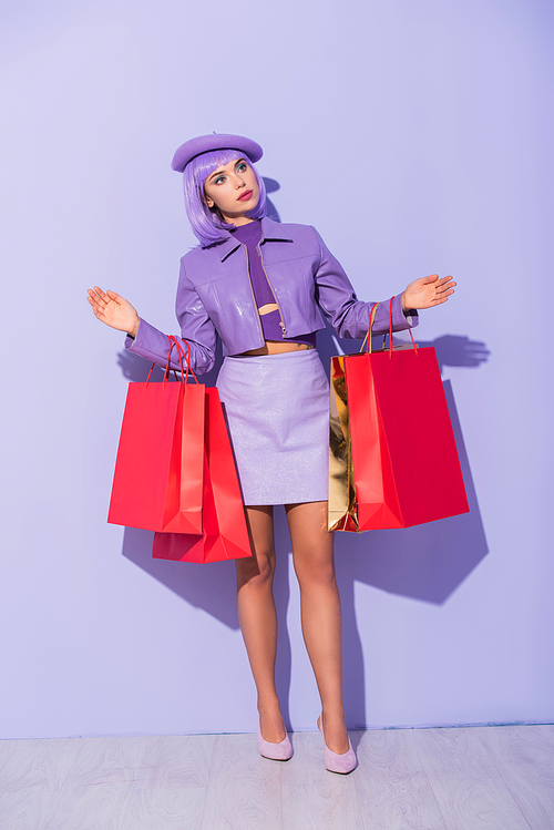 young woman dressed in doll style with red shopping bags on violet colorful background