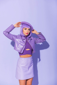 young woman dressed in doll style in beret posing on violet colorful background