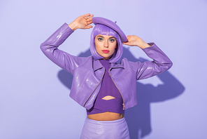 young woman dressed in doll style in beret posing on violet colorful background