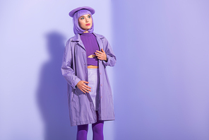 young woman dressed in doll style in beret posing on violet colorful background