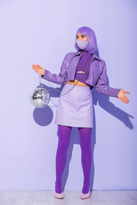young woman dressed in doll style in medical mask with disco ball on violet colorful background