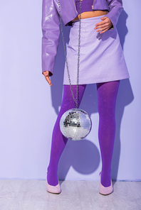 cropped view of young woman dressed in doll style with disco ball on violet colorful background