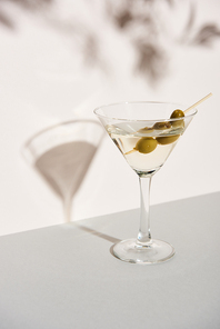 Martini with olives on white background with shadow