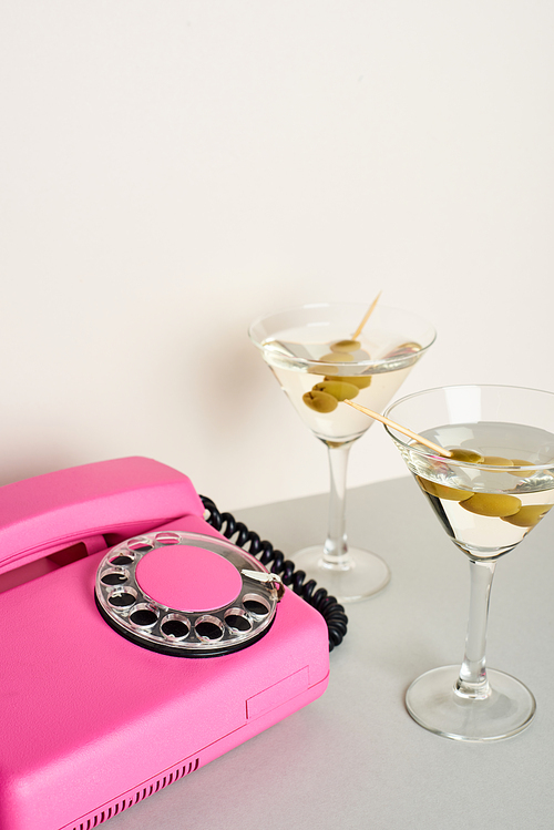 Pink retro telephone with martini cocktails on white background