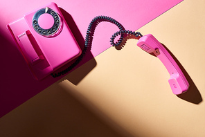 Top view of pink telephone with shadow on colorful surface