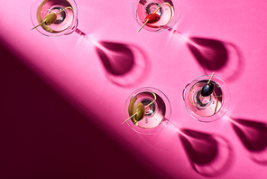 Top view of martini cocktails with shadows on pink background
