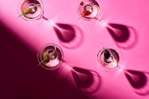 Top view of martini cocktails with olives on bright pink background