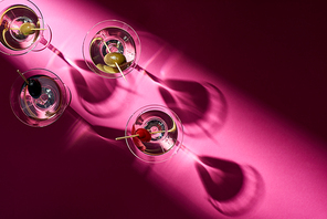 Top view of martini cocktails with olives on pink background