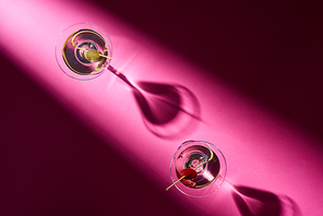 Top view of two cocktails with shadows on pink background