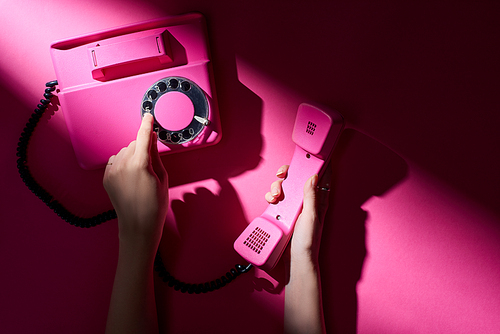 Cropped view of woman using retro telephone on pink background