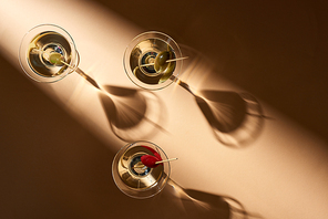 Top view of martini cocktails with olives on beige background