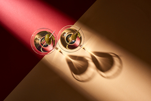 Top view of cocktails with olives with shadows on red and beige background