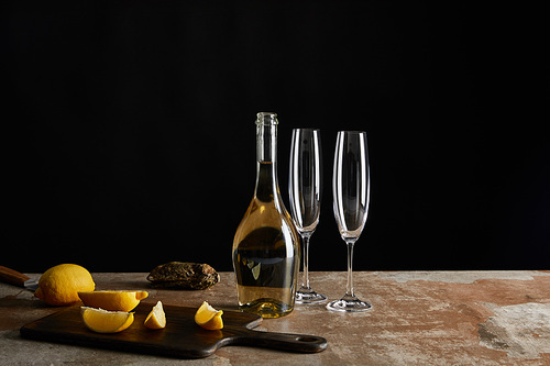 delicious oyster in shell near lemons and bottle with sparkling wine isolated on black