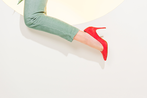 cropped view of young woman in stylish pants and red high heels on white with copy space